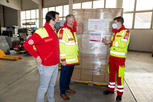 Drei Rettungskräfte besprechen Hilfsgüter zur Unterstützung in Notlagen.