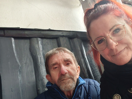 Ein älterer Mann und eine Frau posieren gemeinsam vor einer Wand.