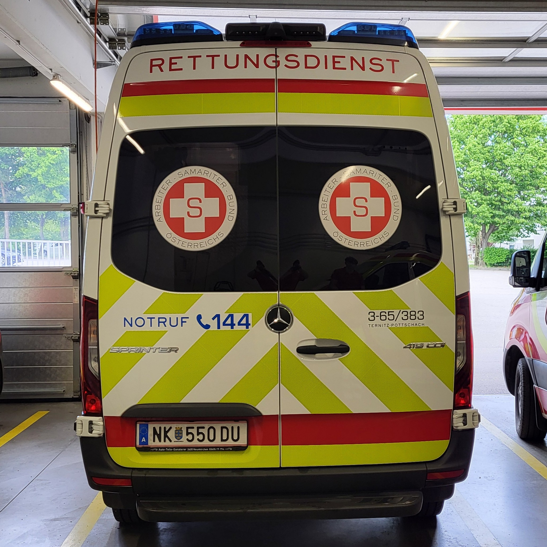 Rettungswagen mit rotem Kreuz und Notrufnummer 144 in einer Garage.