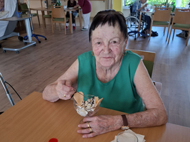 Eine ältere Frau genießt ein Eis in einem gemütlichen Raum.