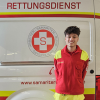 Rettungssanitäter steht vor einem Rettungswagen.