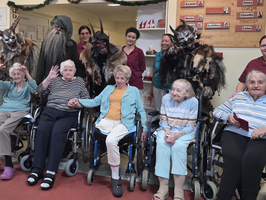 Gruppenfoto mit älteren Menschen in Rollstühlen und verkleideten Figuren.