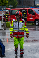Ein Rettungssanitäter in leuchtender Uniform geht bei Regen durch die Straße.