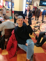 Ein Mann sitzt und hebt seine Hand mit einem Finger nach oben.