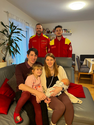 Familie mit zwei kleinen Kindern posiert freundlich mit zwei Rettungssanitätern.