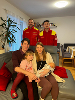 Familie mit zwei kleinen Kindern posiert freundlich mit zwei Rettungssanitätern.