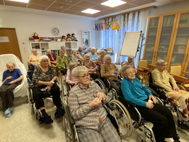 Eine Gruppe älterer Menschen sitzt in einem Aufenthaltsraum zusammen.