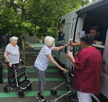 Ältere Frauen erhalten Eis von einem Verkaufswagen in einem Park.