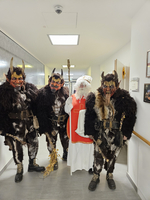 Vier verkleidete Figuren in einer Flur, zwei teufelsähnlich und eine als Nikolaus.