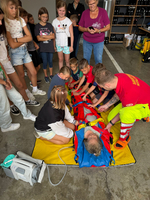 Kinder schauen zu, wie ein Kind von einem Sanitäter in einer Vakuummatraze immobilisiert wird.