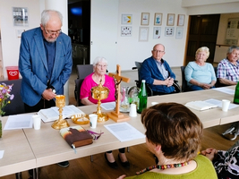 Eine Gruppe von Menschen versammelt sich zu einer feierlichen Zeremonie am Tisch.