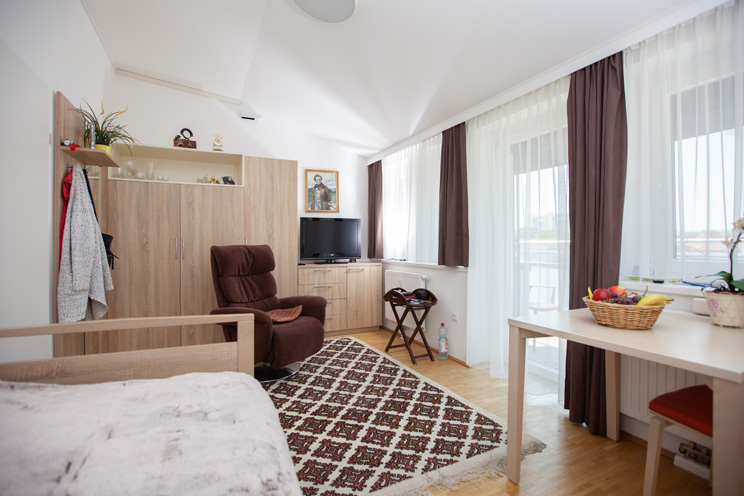 Senioren-WG Kapaunplatz Einzelzimmer mit Bett, Tisch, Schrank, Fernsehsessel