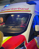 Ein Mädchen sitzt im Rettungswagen hinter dem Lenkrad.