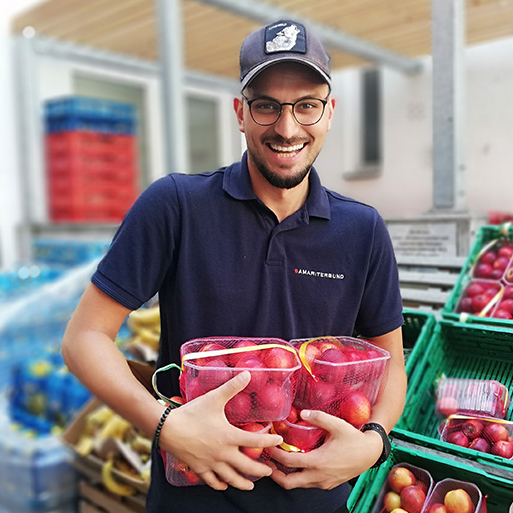 Ehrenamtlicher Sozialmarkt Mitarbeiter hält verpackte Pfirsiche und lächelt in Kamera