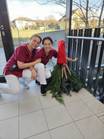 Zwei Frauen in roten Hemden posieren mit einem dekorierten Christbaum.
