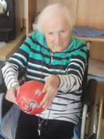 Eine ältere Frau hält einen roten Ball in den Händen.