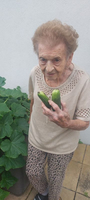 Eine ältere Frau hält zwei frische Gurken in der Hand.