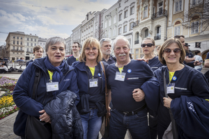 Fünf Menschen in T-Shirts des Samariterbundes lächeln vor einer Stadtkulisse.