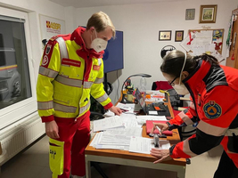 Zwei Sanitäter im Einsatz prüfen und bearbeiten Dokumente am Tisch.