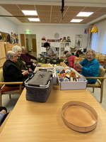 Senioren basteln gemeinsam an einem Tisch mit verschiedenen Materialien.