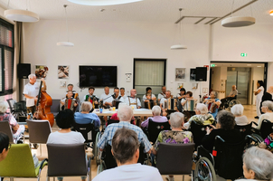 Musikgruppe spielt in einem Seniorenheim, Zuhörer genießen die Darbietung.