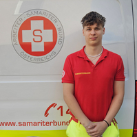 Ein Sanitäter in Uniform steht vor einem Rettungsauto des Samariterbundes.