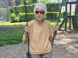 Eine ältere Frau sitzt auf einer Schaukel im Freien.