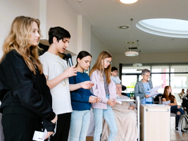 Jugendliche präsentieren ein Programm vor älteren Menschen in einem Gemeinschaftsraum.
