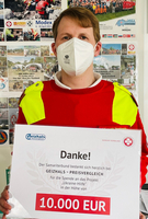 Eine Person in roter Kleidung hält ein Dankeschön-Schild über eine Spende von 10.000 EUR.
