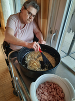 Eine Frau rührt Zwiebeln in einem großen Topf neben gewürfeltem Schinken.