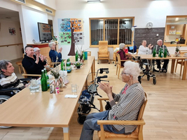 Gruppe älterer Menschen applaudiert in einem Gemeinschaftsraum.