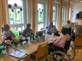 Eine Gruppe älterer Menschen sitzt an einem Tisch und unterhält sich.