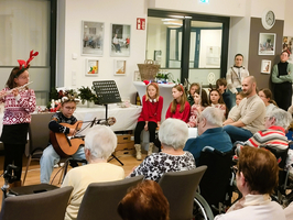 Kinder führen ein musikalisches Weihnachtsprogramm für ältere Menschen auf.