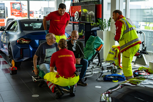 Rettungskräfte helfen Patienten in ein Autohaus mit medizinischer Versorgung.