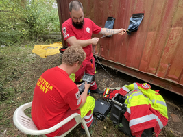 Zwei Rettungskräfte arbeiten an einem Container mit technischem Equipment.