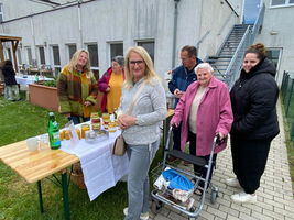 Mehrere Personen stehen an einem Tisch mit Gläsern und Getränken im Freien.