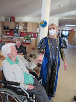 Frau im Rollstuhl spricht mit einer verkleideten Person in blauem Kleid.