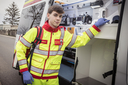 Ein Sanitäter in gelber Uniform steht an einem Krankenwagen.