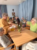 Senioren dekorieren gemeinsam einen Osterbaum mit bunten Eiern.