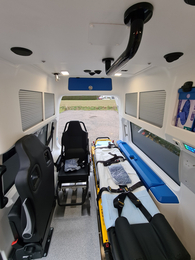 Innenansicht eines Rettungswagens mit Sitz und Tragbahre.