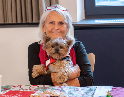 Eine ältere Dame hält ihren Hund in den Armen, Weihnachtsfeiern, Senioren-WGs