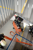 Feuerwehrleute steigen eine Treppe hinunter und tragen eine Trage.