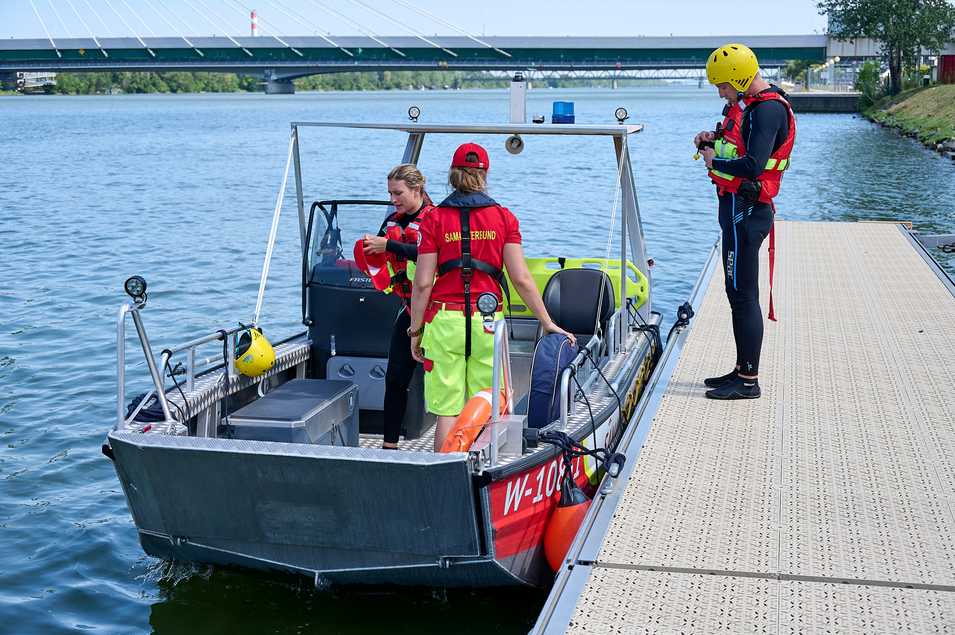 Boot der Wiener Wasserrettung am Steg mit drei Sanitätern, die sich auf einen Einsatz vorbereiten, Wasserrettung 