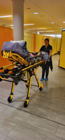 Eine Person schiebt eine Tragbahre durch einen flur mit gelben Schränken.