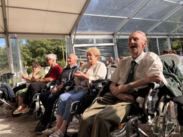 Senioren applaudieren und lachen während einer Veranstaltung im Zelt.