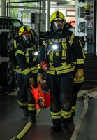 Zwei Feuerwehrleute tragen eine orange Tasche mit einer Person heraus.