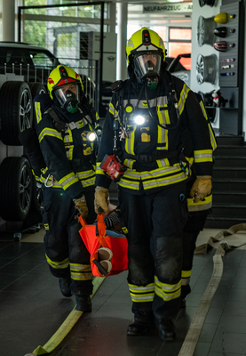 Zwei Feuerwehrleute tragen eine orange Tasche mit einer Person heraus.
