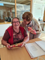 Zwei Frauen lachen und halten Geschenke in einer freundlichen Umgebung.