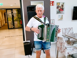 Ein älterer Mann spielt Akkordeon in einem gemütlichen Raum.