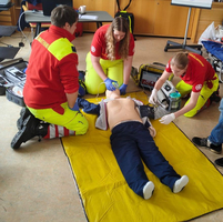 Drei Personen führen Erste Hilfe an einer Übungspuppe durch.